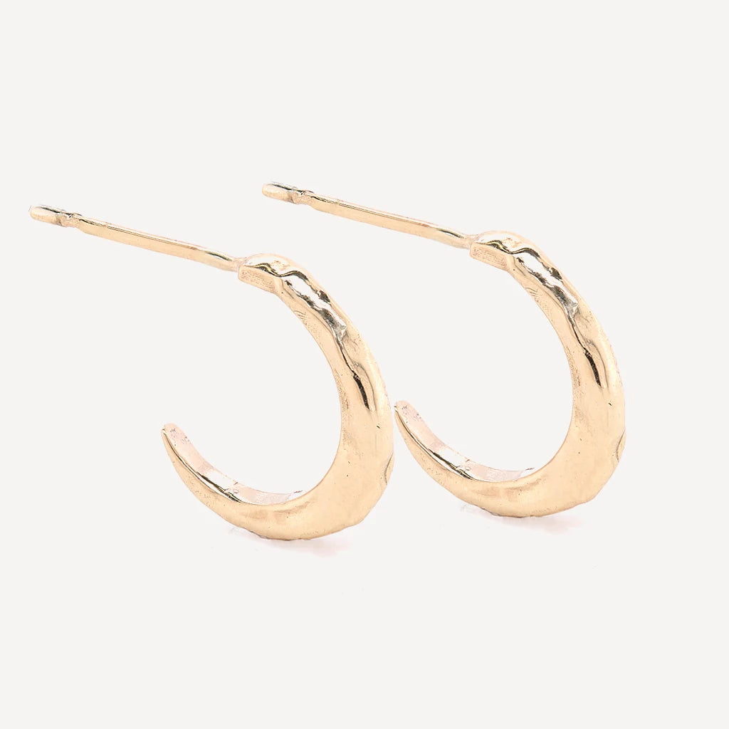 Gold crescent hoop stud earrings with a textured organic finish in polished gold vermeil on a soft beige background.