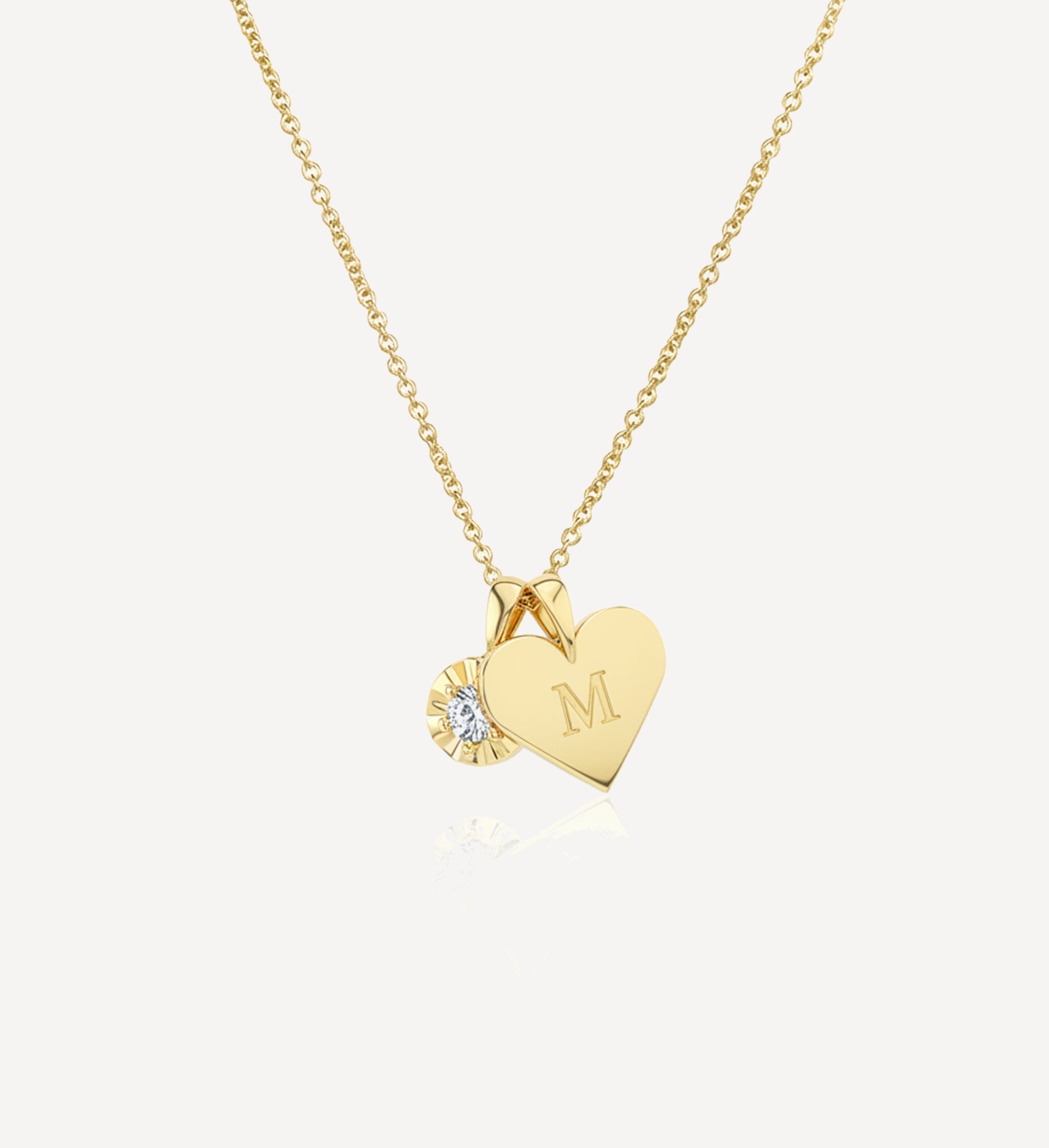 Solid gold keepsake charm necklace featuring a personalised heart initial charm engraved with the letter M and a round diamond charm suspended from a fine yellow gold chain