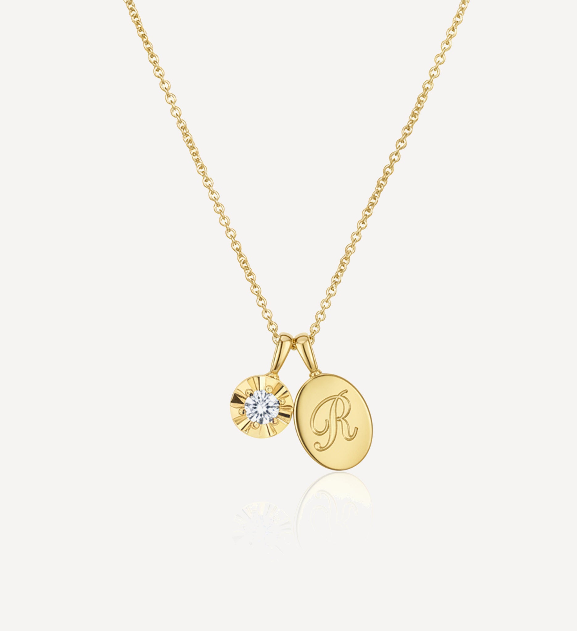 Solid gold keepsake charm necklace featuring a personalised oval initial charm engraved with the letter R and a round diamond charm suspended from a fine yellow gold chain