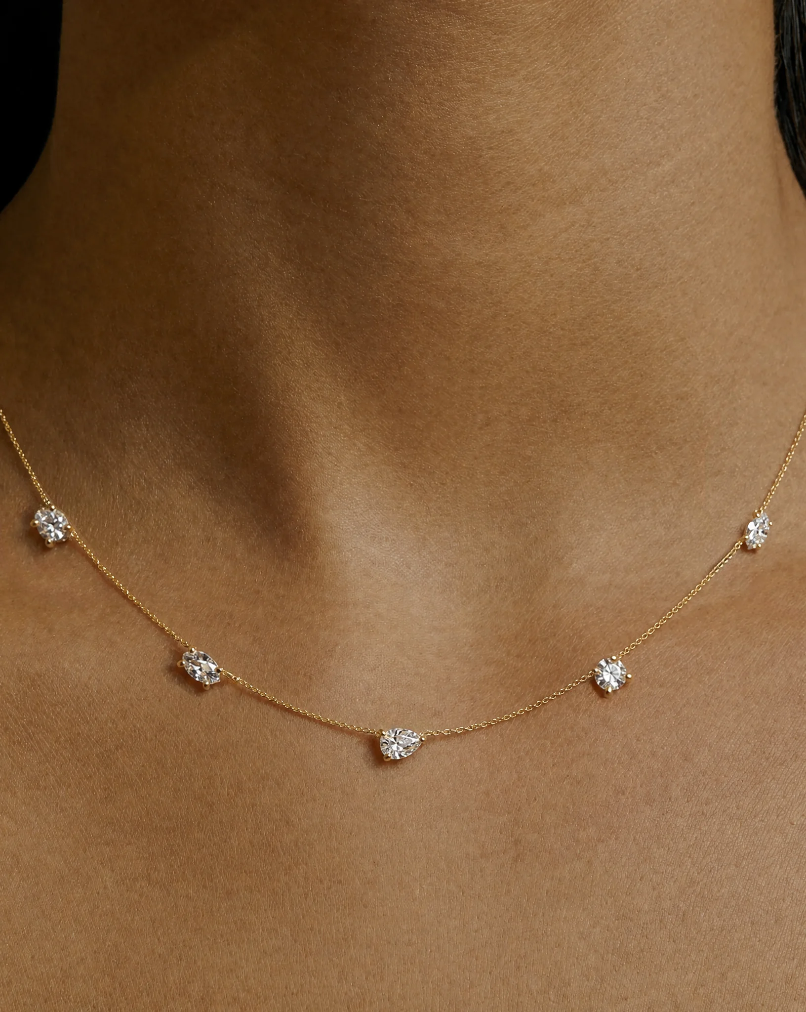 Nola Diamond Satellite Necklace by HLSK Jewellery in yellow gold featuring a pear-cut centre diamond with round brilliant satellite diamonds on a fine chain, worn on a model.