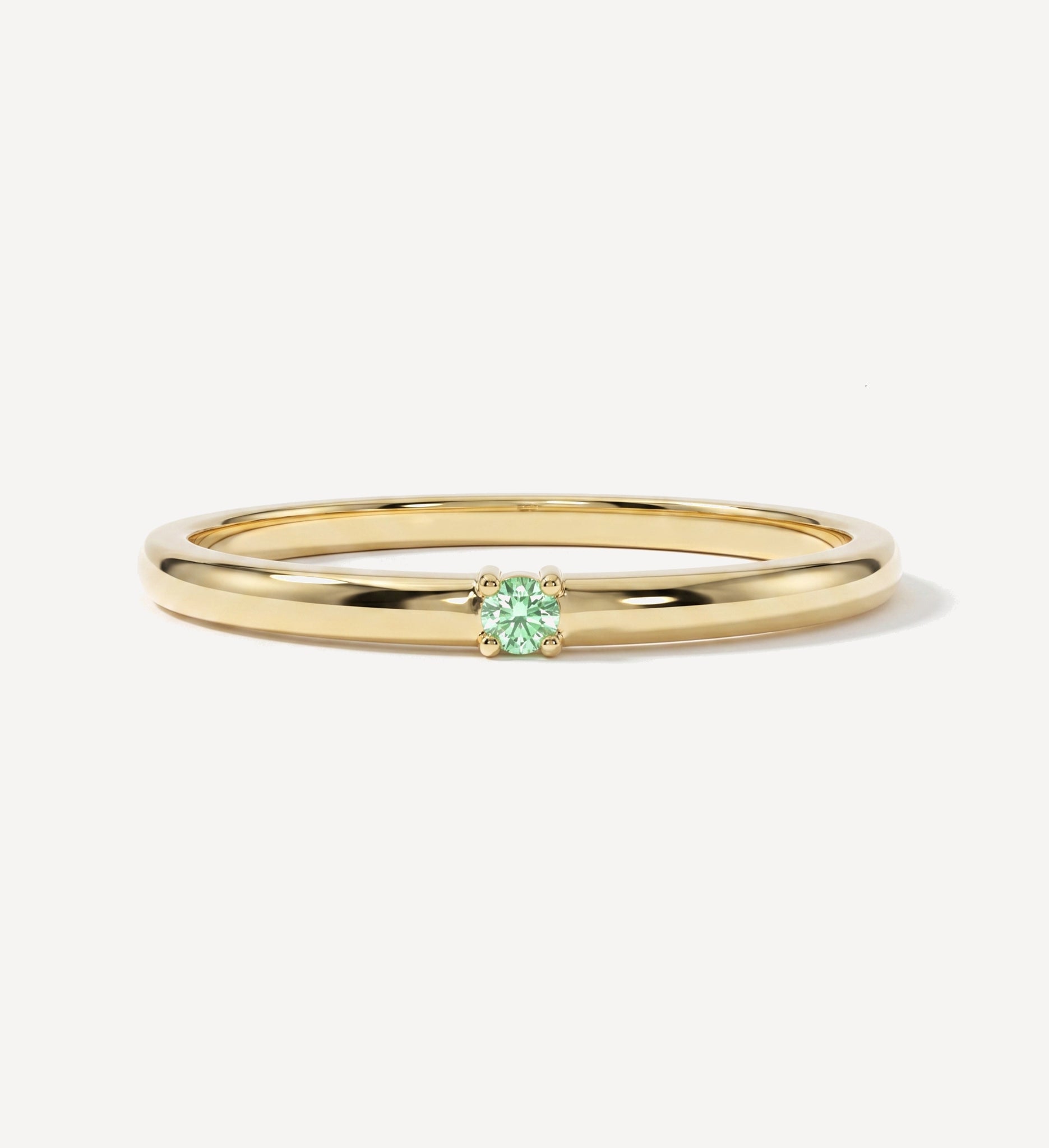 Plain single birthstone solid gold ring featuring a round green birthstone in a minimalist four-prong setting on a polished yellow gold band