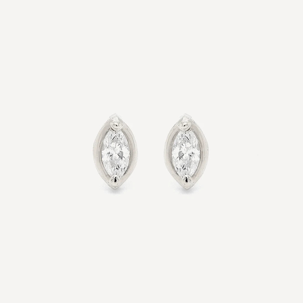 Silver marquise diamond stud earrings featuring brilliant marquise-cut stones in a polished sterling silver setting on a soft beige background.