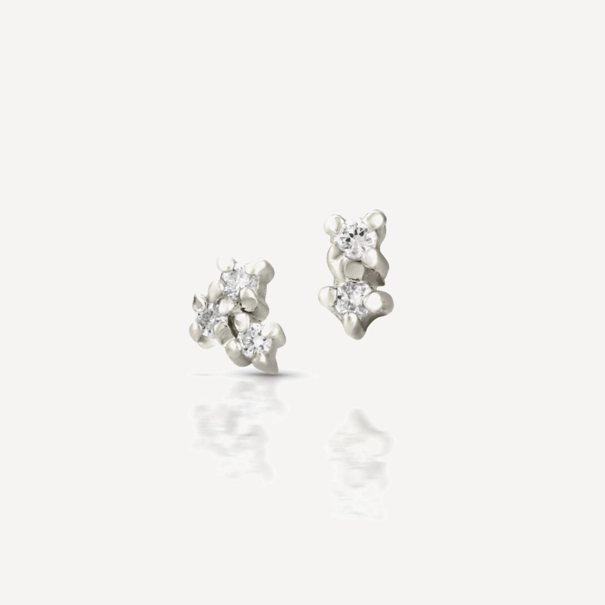 Sterling silver diamond cluster stud earrings featuring a delicate multi-stone floral cluster design with brilliant-cut diamonds on a soft beige background.