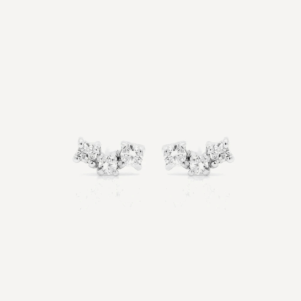 Sterling silver diamond cluster stud earrings featuring three brilliant-cut stones in a delicate clustered design on a soft beige background.